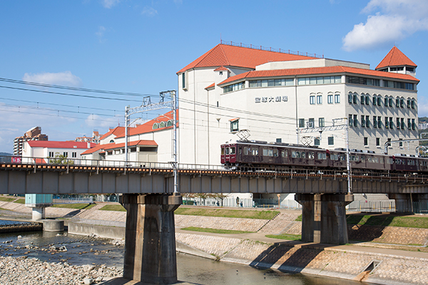 A Hankyu train passes by the Takarazuka Grand Theater and crosses the Mukogawa River